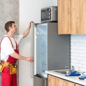 Worker repairing fridge in kitchen
